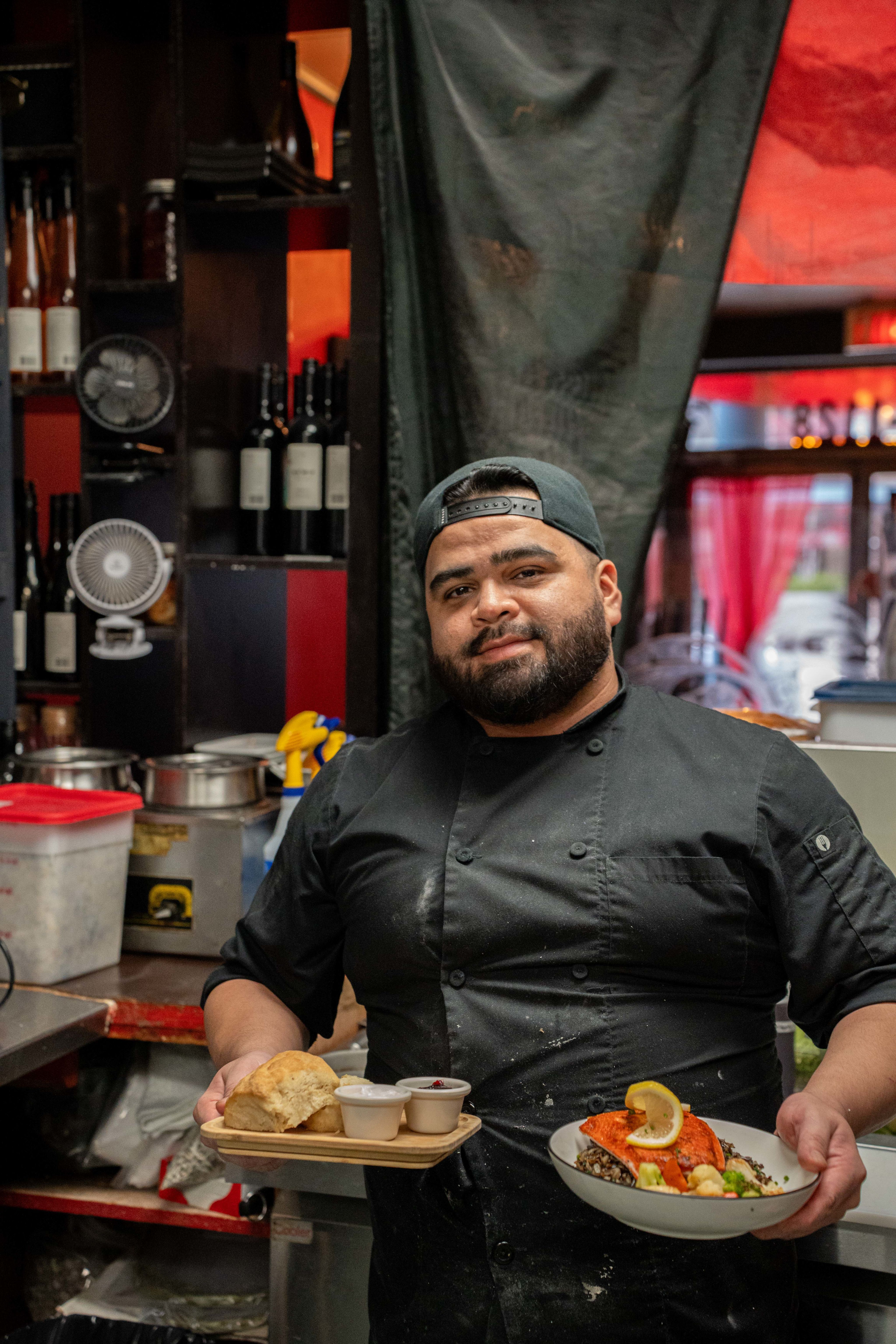 Chef Jordan Barton holding plates of bannock with butter and jam, and "Fiss n' Rice" that he prepared