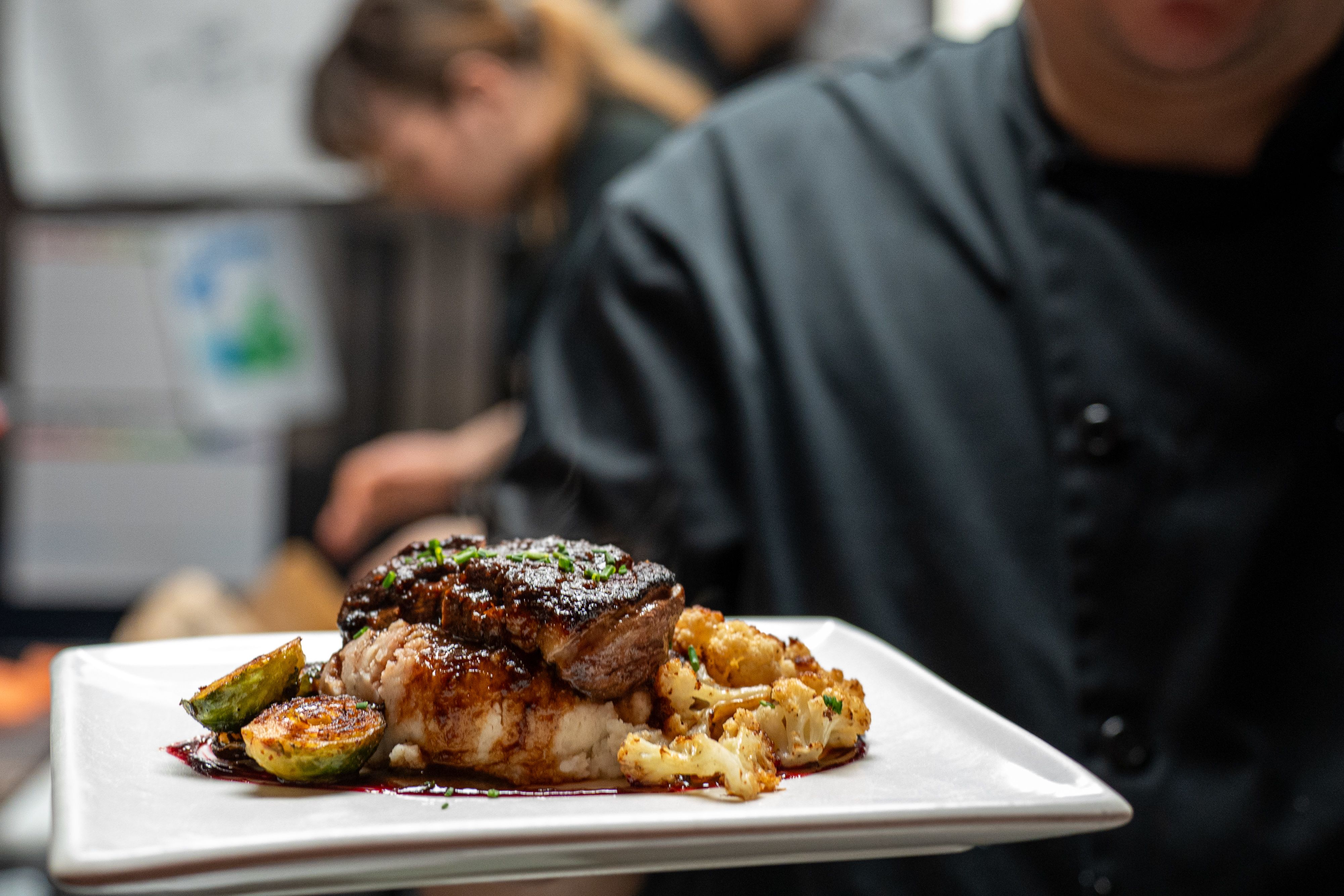 Seared duck breast on a bed of mashed potatoes, with a demi glaze and seasonal vegetables 